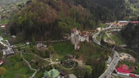 Panorama-Luftdrohne-Fliegt-über-Schloss-Bran,-Rumänischer-Draculawald,-Bergdorf