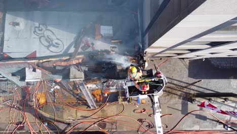 Building-fire-in-Canada-with-firefighters-up-high-with-ladder,-aerial-top-down-view