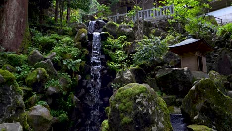 Beautiful-scenery-inside-lush-forest-temple-in-summer-with-waterfall