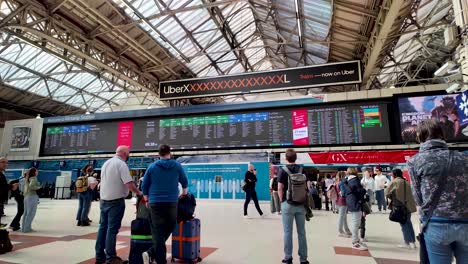 Los-Viajeros-Esperando-En-El-Vestíbulo-De-La-Estación-Victoria-Mirando-El-Tablero-De-Horarios-De-Trenes