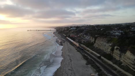 Amtrak-train-heads-south-along-the-scenic-coast-in-San-Clemente,-California-during-the-day