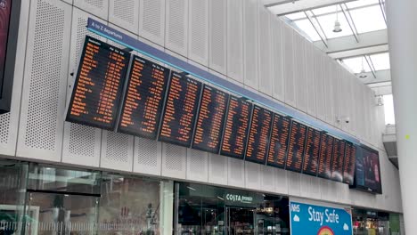 Row-Of-Train-Timetables-Hanging-Off-Wall-In-London-Bridge-Station
