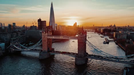 Drone-Dando-Vueltas-Sobre-El-Tráfico-En-El-Puente-De-La-Torre-Con-Barcos-En-El-Támesis-Al-Atardecer,-Londres