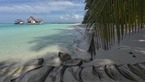 Aufnahme-Des-Strandes-Im-Kooddoo-Resort-Auf-Den-Malediven,-Zeigt-Klares-Wasser,-Das-An-Einen-Sandstrand-Plätschert