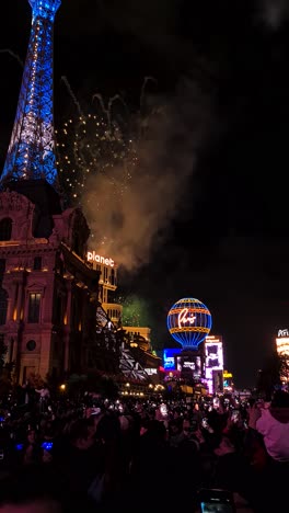 Video-Vertical,-Celebración-Del-Año-Nuevo-En-Las-Vegas,-Estados-Unidos,-Fuegos-Artificiales-Sobre-Los-Edificios-Del-Hotel-Casino-Y-Gente-En-El-Strip