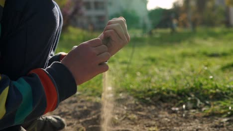 Close-up-120-fps-Slow-motion-shot-of-caucasian-boy-playing-with-soil-in-a-field,-on-a-sunny-day