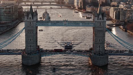 Drone-Retreating-Shot-of-Traffic-on-Tower-Bridge-with-Boats-on-the-Thames-at-Sunset,-London