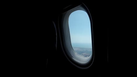 Within-the-aircraft's-cabin,-our-gaze-meets-the-window,-its-frame-enclosing-a-beautiful-blue-sky