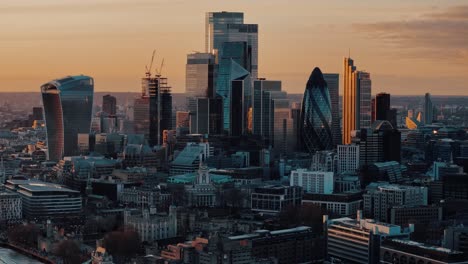 Slow-Circling-Drone-Shot-of-City-of-London-Skyscrapers-at-Sunset-with-Golden-Light-Reflections