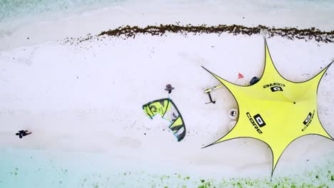 A-kite-surfer-preparing-equipment-on-snowy-ground-at-isla-sardina,-aerial-view