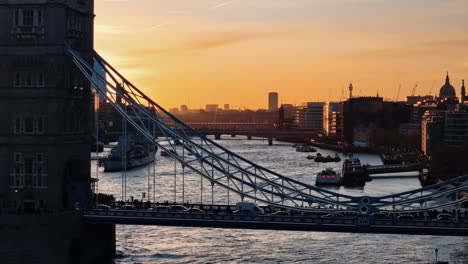 Close-Up-Shot-of-Traffic-on-Tower-Bridge-with-Sunset,-London-Skyline,-and-River-Thames