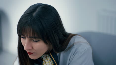 Close-up-of-a-beautiful-young-woman-with-long-dark-hair-working-hard-in-office,-focusing-at-a-task-in-slow-motion