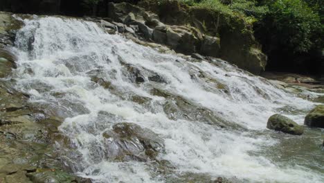 Woman-sits-in-waters-of-Goa-Rang-Reng-waterfall-on-Bali-island-in-Indonesia