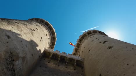 Castillo-Filmado-Hasta-La-Cima-Con-Vistas-A-Un-Día-Soleado-Con-Una-Bandera-Española-Ondeando-En-La-Cima-Del-Castillo.