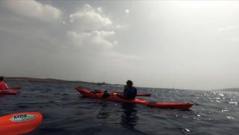 A-group-of-kayakers-stop-and-wait-for-the-ferry-to-pass-between-Gozo-and-Malta-before-paddling-onto-the-island-of-Comino-in-the-Mediterranean-Sea