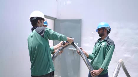 Engineer-Using-Angle-Grinder-To-Cut-Thick-Cable-Held-Up-By-Colleagues-At-Warehouse-In-Pakistan