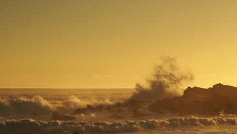 Rough-Sea-Waves-Crashing-On-Rocks-Creating-Huge-Spray-During-Golden-Sunset---Wide-Pan-Shot