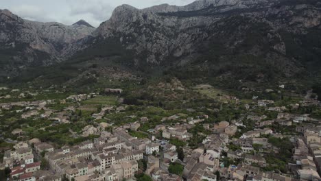 Ciudad-Medieval-De-Sóller-Rodeada-De-Una-Gran-Montaña-En-La-Isla-De-Mallorca,-Aérea