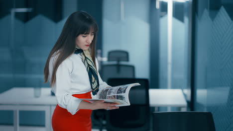 High-executive-browsing-through-the-designer-magazine-pages-in-an-office-wearing-red-skirt-and-white-shirt