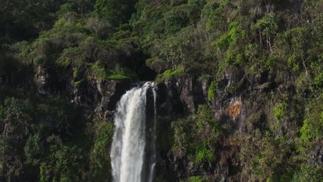 Scenic-waterfall-plunge-over-jungle-cliff-edge-on-Maui-North-Shore,-drone-slomo