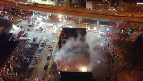 Elevated-night-view-of-a-building-on-fire-in-Montreal,-smoke-billowing,-emergency-response-underway,-aerial-view