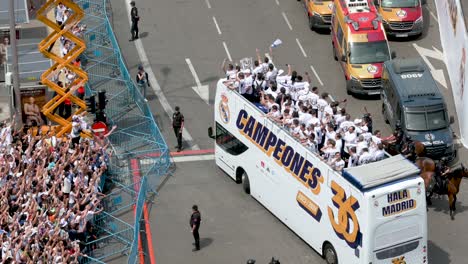 Riding-on-a-bus,-Real-Madrid-players-celebrate-winning-the-36th-Spanish-soccer-league-championship,-the-La-Liga-title-trophy,-at-Cibeles-Square,-where-thousands-of-fans-gathered-in-Madrid