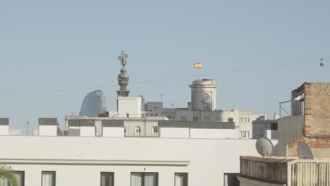 Cable-transportation-over-Barcelona-city-monuments-and-buildings,-Columbus-statue-and-famous-hotel
