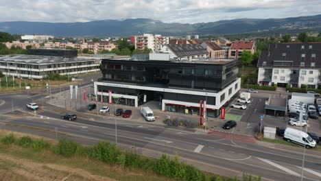 Aerial-of-large-office-building-along-a-calm-road-in-Gland,-Switzerland