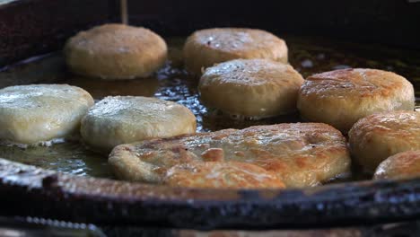 Pastel-De-Carne-Chino-Recién-Hecho-Y-Pastelería-De-Frijoles-Rojos-Cocinado-Y-Chisporroteando-En-Una-Sartén-De-Aceite-Caliente,-Primer-Plano-De-La-Popular-Delicia-Asiática-Cocinada-En-Proceso