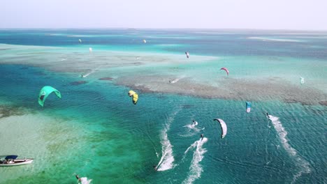 Colorful-kitesurfers-gliding-over-clear-blue-waters-at-cayo-vapor,-vibrant-ocean-scene,-aerial-view