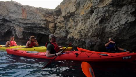 A-tourist-guide-shows-and-explains-a-big-Maltese-natural-sea-cave-to-a-group-of-kayakers-on-the-island-of-Comino