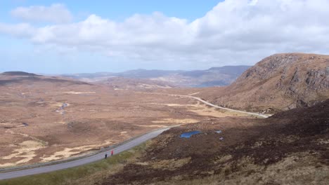 Tourist-and-campervan-visiting-and-exploring-the-rugged-mountainous-landscape-of-Quinag-Sail-Gharbh-in-Assynt-district-of-Sutherland,-highlands-of-Scotland-UK