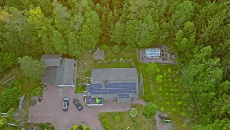 Aerial-rising-shot-of-a-solar-powered,-off-grid-house-in-middle-of-sunlit-forest