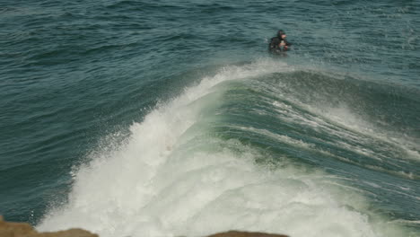 Surfer-catches-and-rides-a-wave-on-a-nice-sunny-day-in-Santa-Cruz,-CA