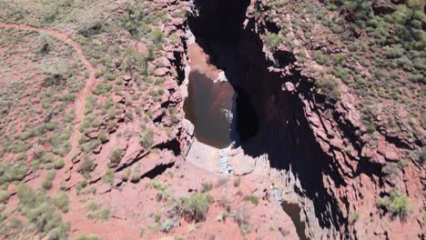 Drone-aerial-flying-backwards-over-Joffre-gorge-and-waterfall-in-Karijini-national-park