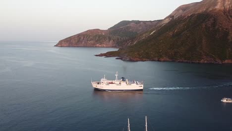 Eine-Fähre,-Die-In-Begleitung-Eines-Kleinen-Motorboots-Von-Einer-Felsigen-Insel-In-Sizilien-Auf-Das-Offene-Meer-Fährt