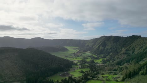 Luftaufnahme-Von-Gepflegten-Grünen-Tälern,-Die-An-Einem-Kalten-Morgen-In-Terceira,-Azoren,-In-Sonnenlicht-Getaucht-Sind,-Mit-Seitlicher-Bewegung,-Die-Einen-Krater-Mit-Einem-See-Darin-Freigibt