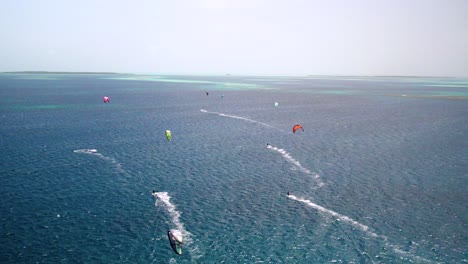 Kite-surfers-glide-over-the-crystal-clear-waters-of-Los-Roques,-a-tropical-paradise-with-vibrant-kites-in-the-air