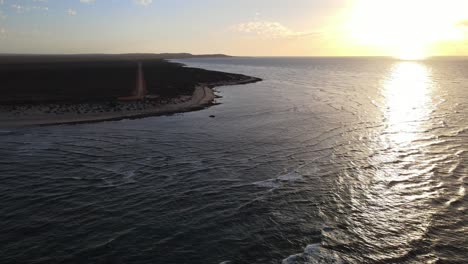 Drone-aerial-during-sunset-over-an-ocean-moving-backwards-to-reveal-a-shipwreck