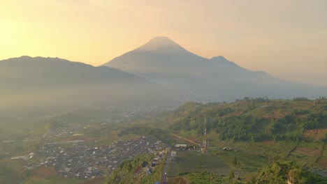 Misty-golden-hour-over-majestic-Mount-Sumbing-in-Indonesia,-aerial-view