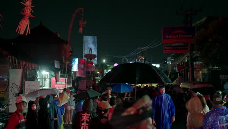 Bajo-Las-Luces-De-La-Ciudad,-Gente-Disfrutando-De-Las-Tradiciones-Indonesias,-Calles-Canggu.