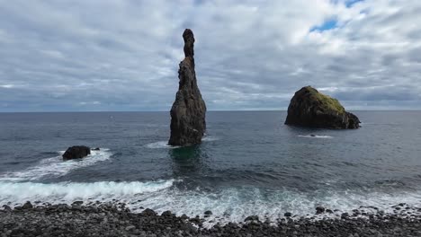 Steinformationen-Im-Ozean-Und-Meer-Mit-Vorbeiziehenden-Wellen,-Die-An-Einem-Bewölkten-Tag-Den-Gepflasterten-Strand-Betreten
