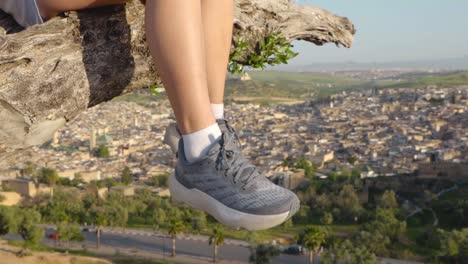 Swing-legs-moving-of-young-woman-sitting-in-a-tree-at-Fez-viewpoint