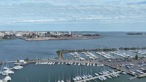 Lauttasaari-marina-with-Jatkasaari-in-the-background,-in-sunny-Helsinki---ascending-drone-shot