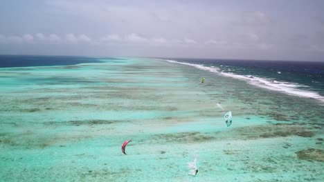 Kite-surfers-gliding-over-the-vibrant,-clear-blue-waters-of-los-roques,-aerial-view