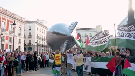 Protesters-at-Puerta-del-Sol-in-Madrid,-Spain,-hold-a-balloon-depicting-a-bomb-as-they-demand-an-end-to-arms-sales-to-Israel-in-support-of-Palestine