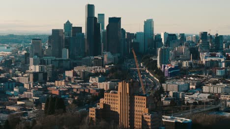 Circling-Drone-Shot-of-Pacific-Tower-with-Seattle-Skyline-and-Freeway-Traffic-at-Sunset