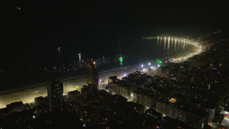 Aerial-footage-at-night-of-a-concert-in-Copacabana,-showing-the-beach-and-the-sea-in-Rio-de-Janeiro