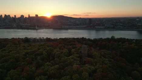 aerial-shot-over-Jean-Drapeau-Park-in-Montreal-city-with-Levis-Tower-in-the-foreground-and-the-city-in-the-background-at-sunset-during-fall-season,-Quebec-Province,-Canada