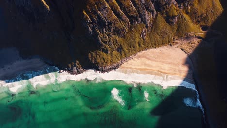 Aerial-shot-of-the-Kvalvika-Beach,-tilting-up-to-reveal-the-Ryten-Mountain-in-the-Lofoten-Islands,-Norway